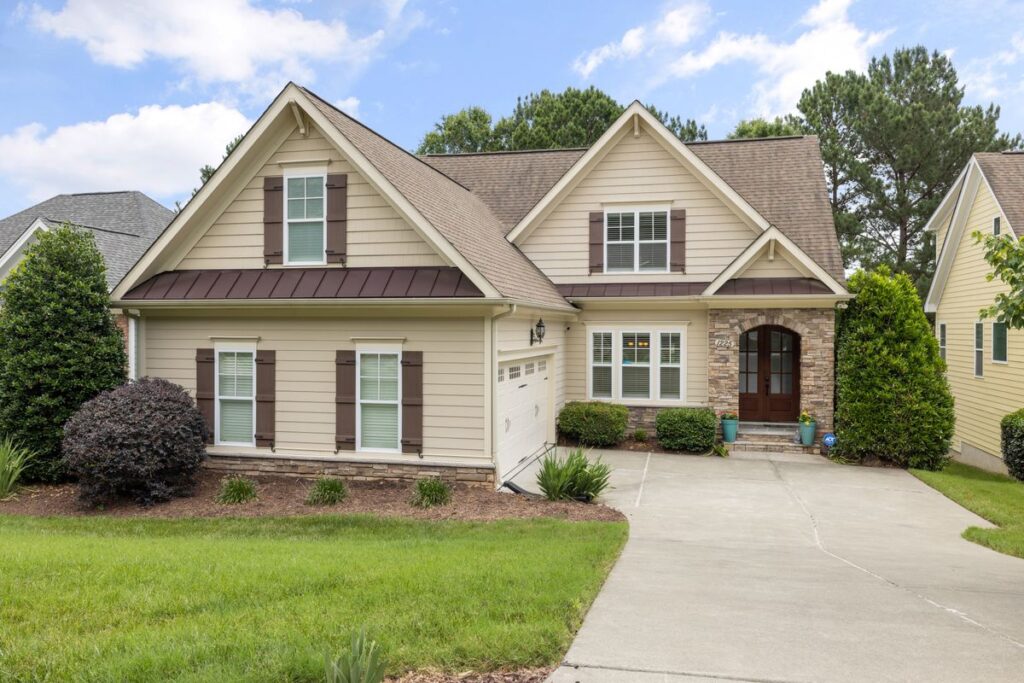 Upscale craftsman home with stone accents and a durable roof on a sunny day