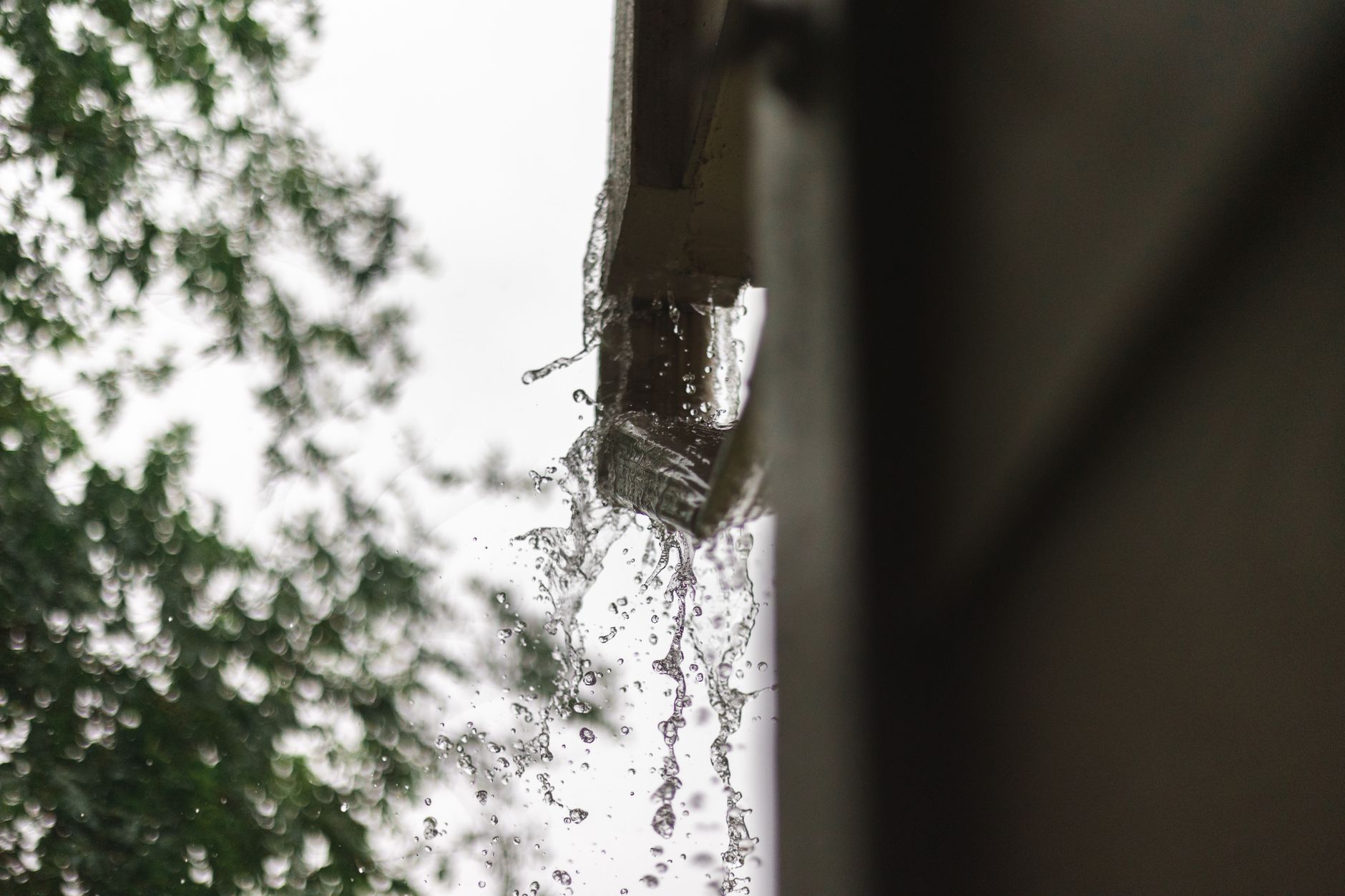 Overflowing rain gutter during a storm - a sign it needs repair
