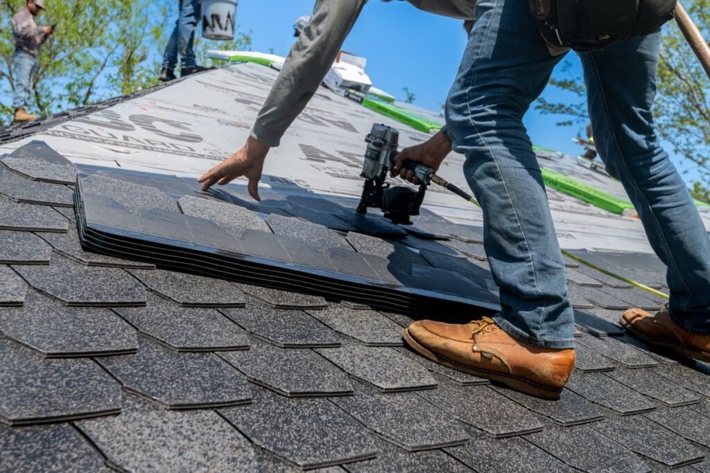 Professional roofer installing architectural asphalt shingles under a blue sky