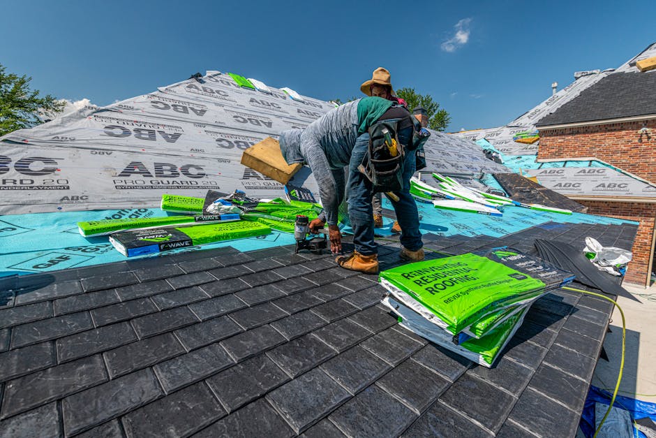 Roofer nailing architectural shingles under a blue sky in Lindon, Utah