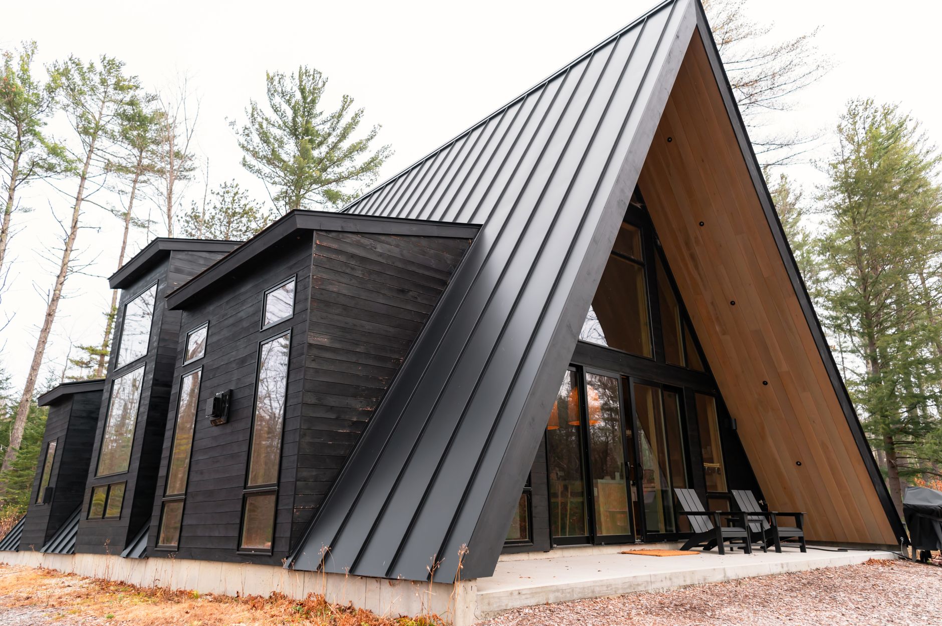 Black standing seam metal roof on a modern A-frame cabin in the pines