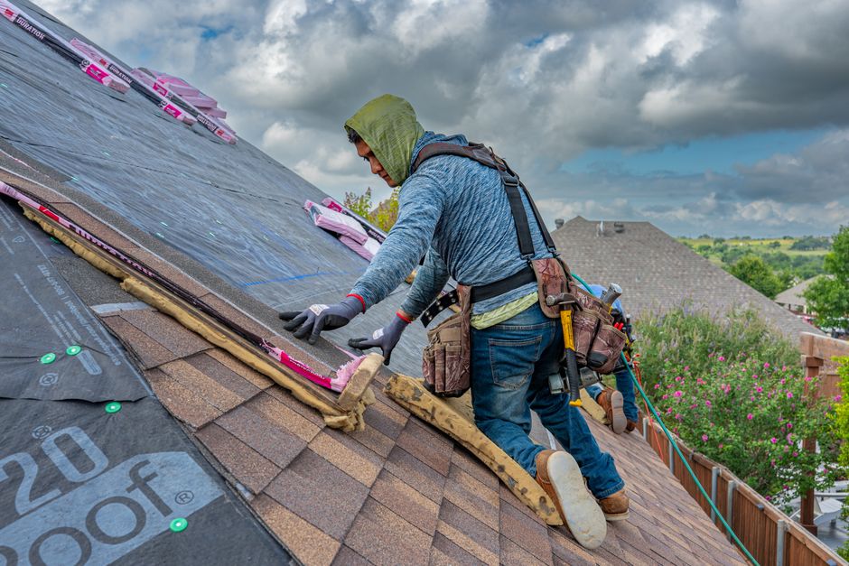Roofer in a safety harness installing underlayment in Pleasant Grove, Utah
