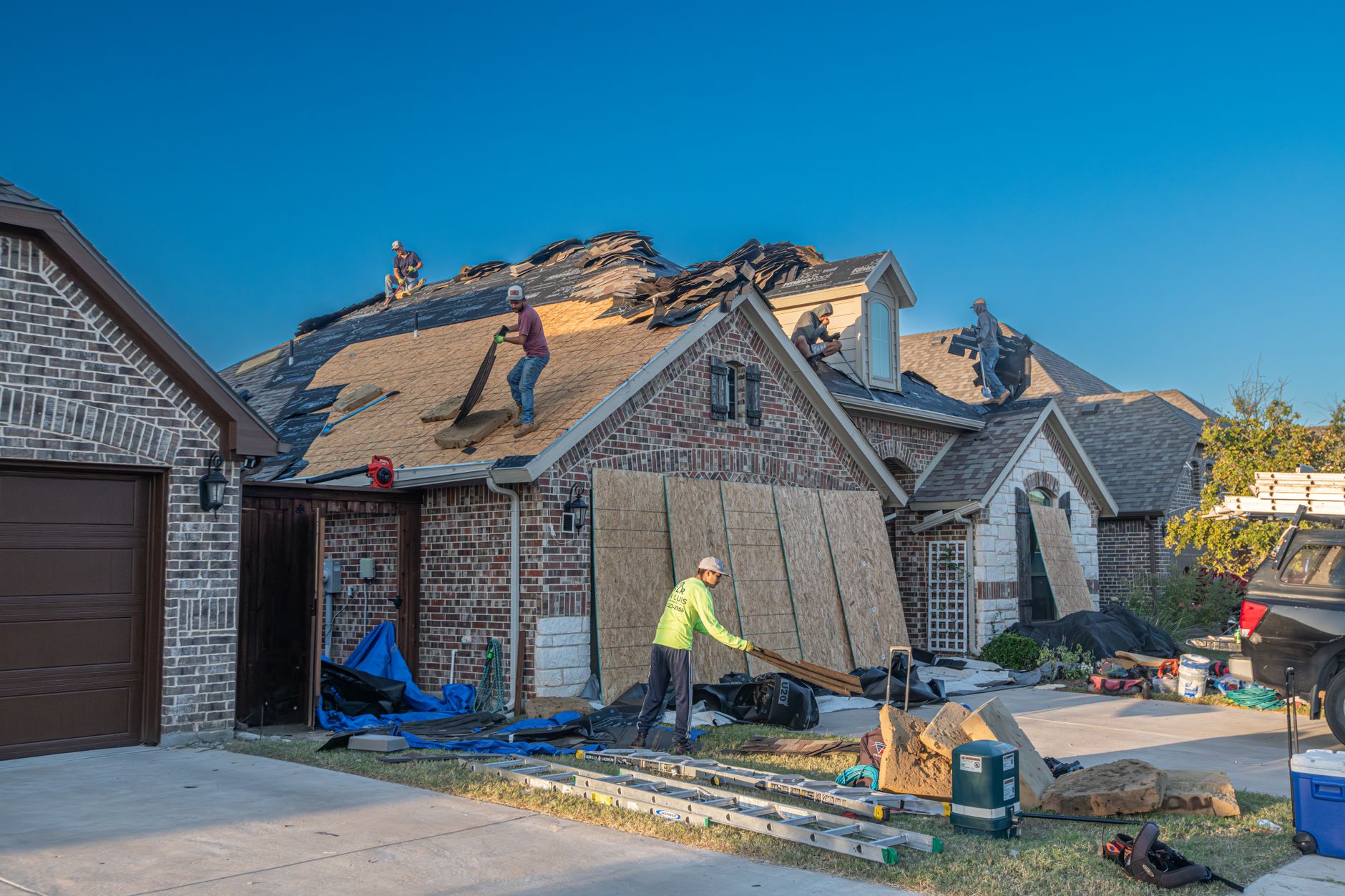 Roof replacement crew tearing off old shingles with the home protected