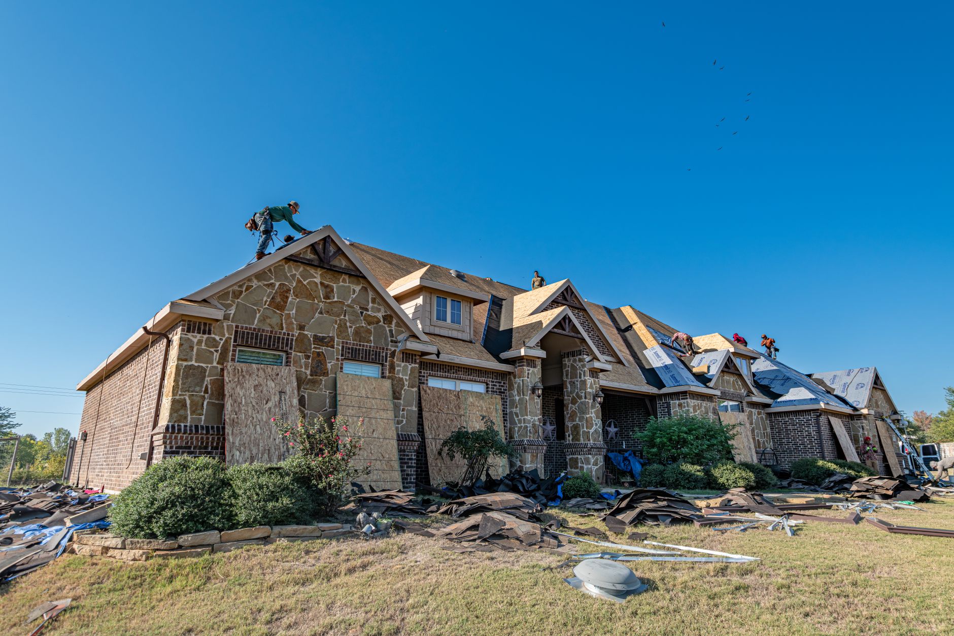 Full tear-off during a roof replacement on a stone-accent home