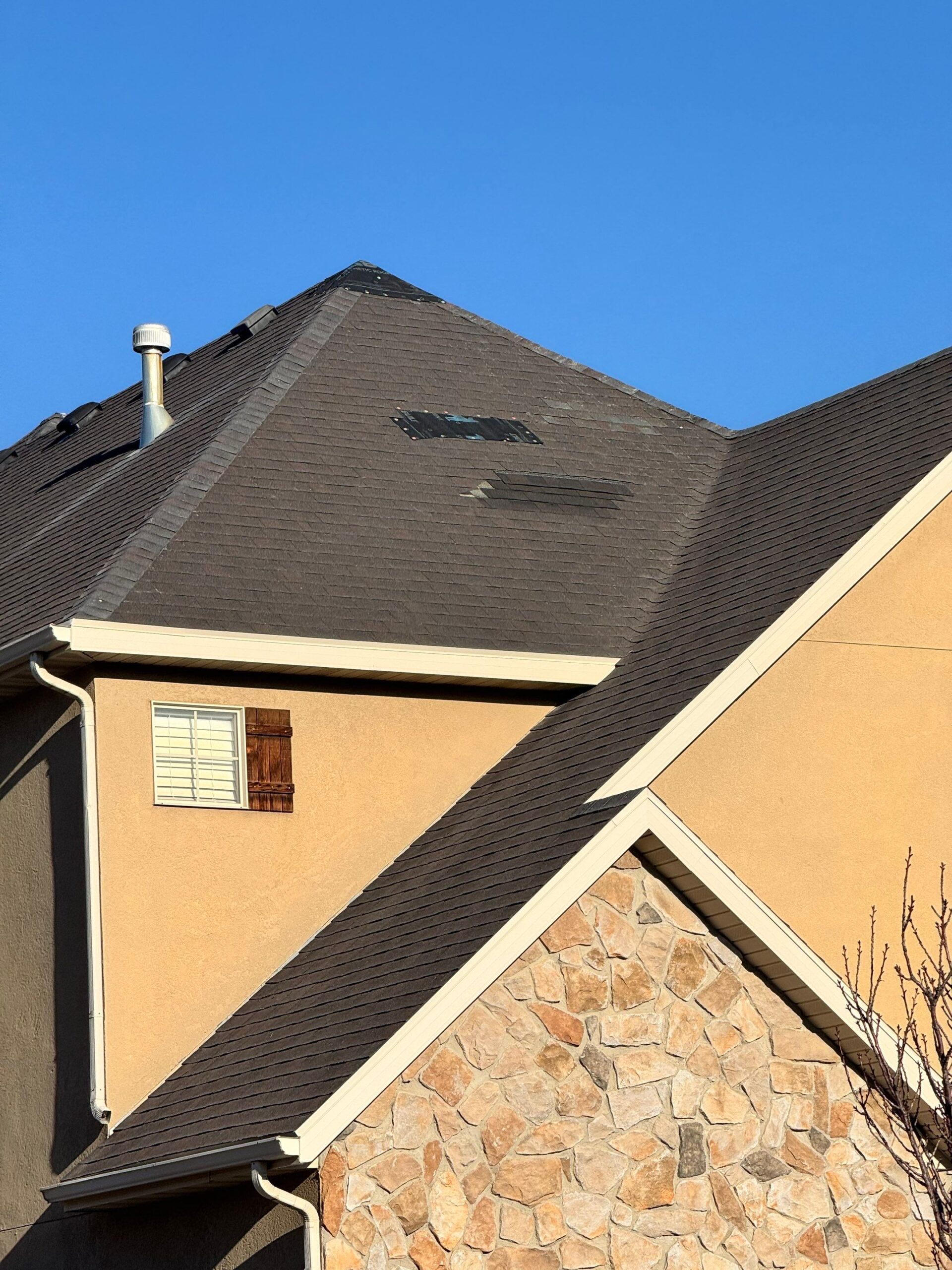 Wind-damaged roof with missing shingles, seen from the ground — Rooval inspection photo, Utah County