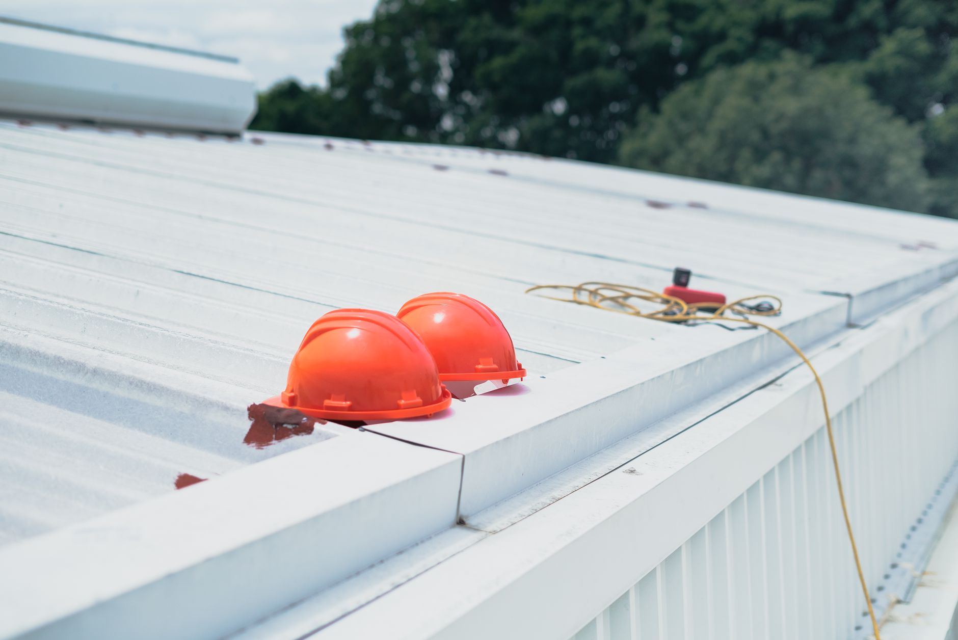 White low-slope commercial roof with safety hard hats