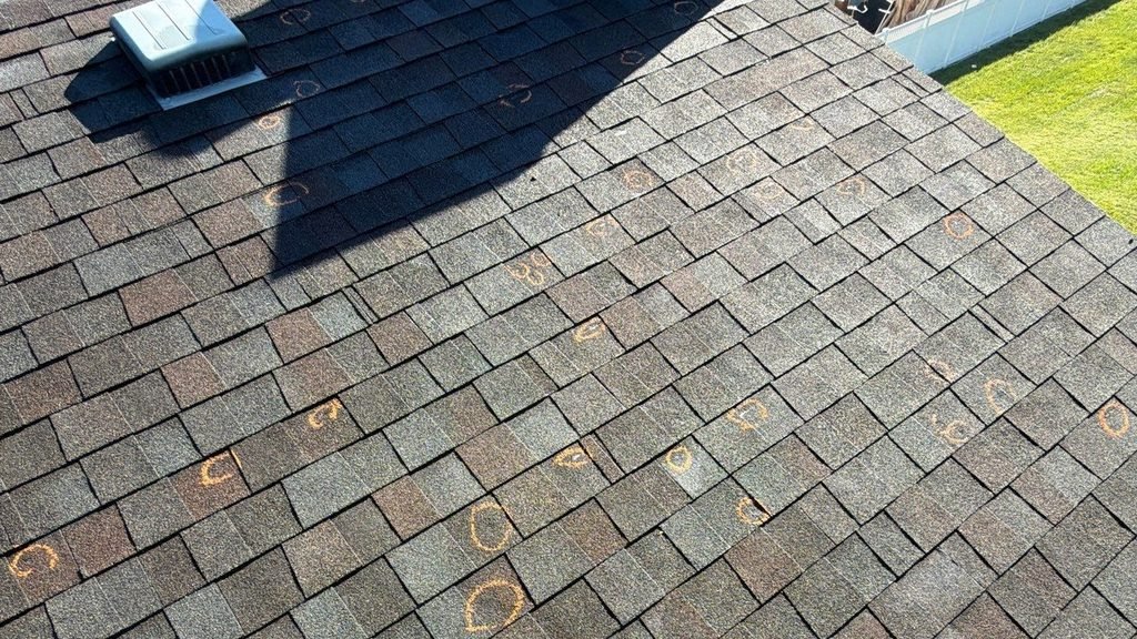 Wide roof inspection slope showing high-density chalk-marked hail strikes next to a metal attic exhaust vent.