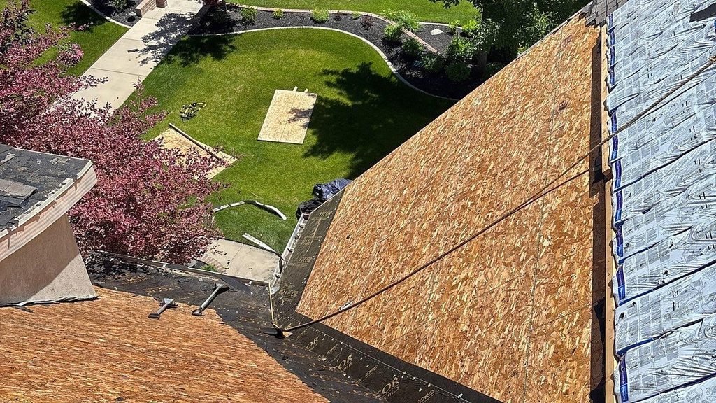 Roof tear-off in progress in Mapleton, Utah, with old shingles removed to bare OSB decking and new shingle bundles staged along the ridge.