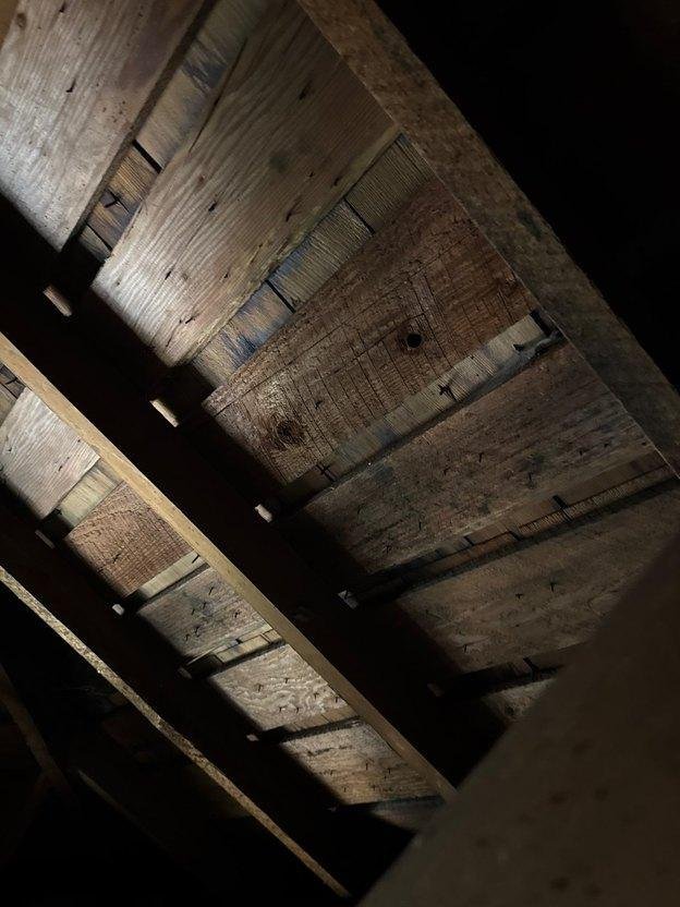 Underside of historic cedar wood shakes visible through wide gaps in original 1x dimensional spaced board roof decking in an Ogden, Utah attic