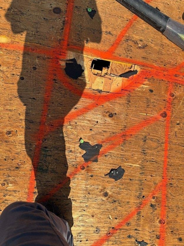 Water-damaged and delaminated CDX plywood roof decking marked with orange spray paint for surgical replacement in Salt Lake County, Utah