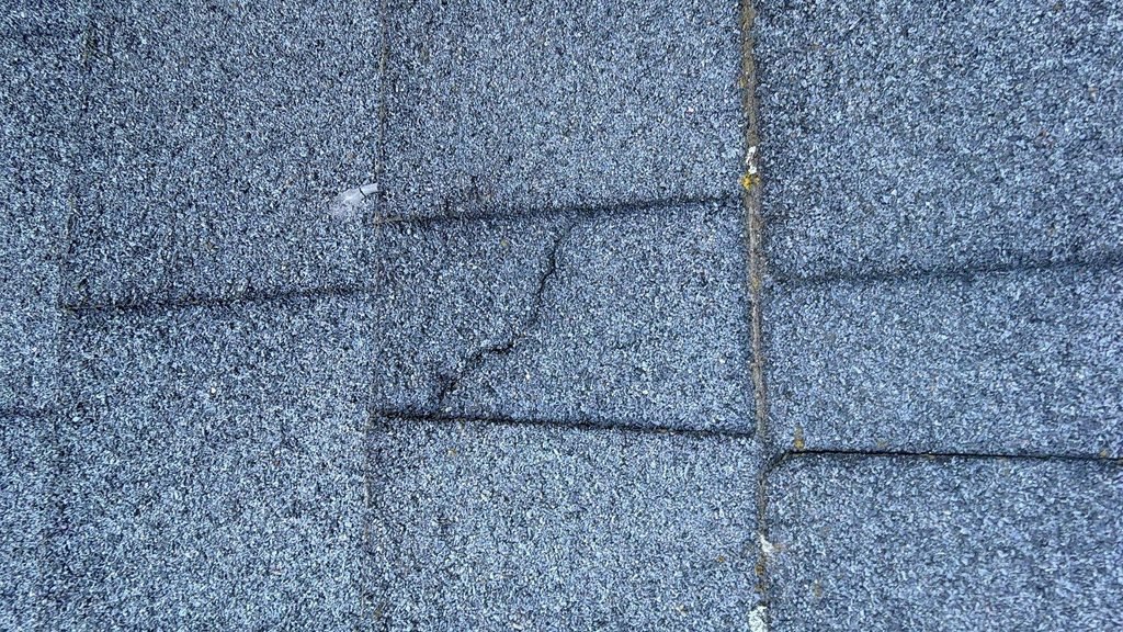 Cracked 3-tab asphalt shingle tab on a roof in American Fork, Utah.