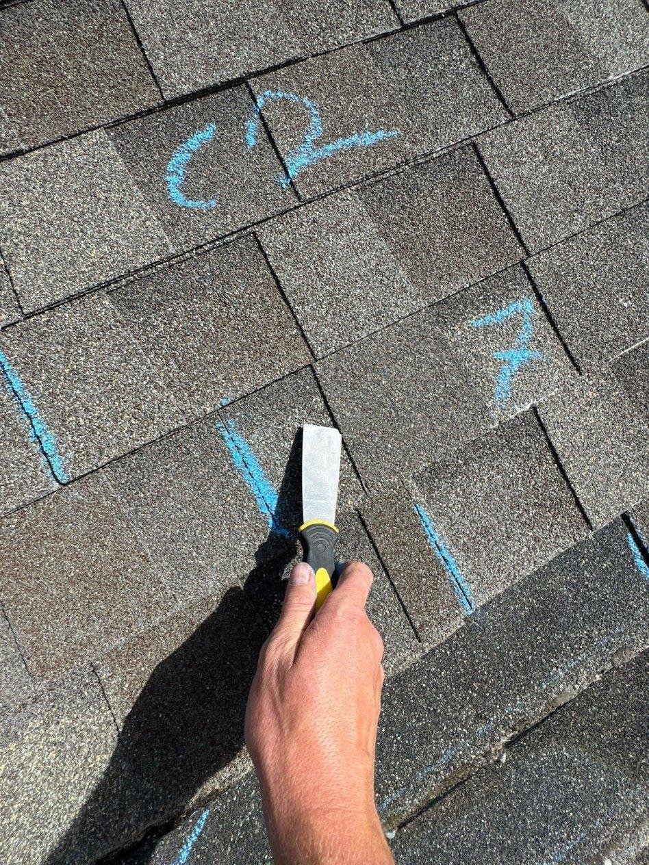 Blue chalk marks on architectural asphalt shingles showing damage points found during a roof inspection in Lehi, Utah