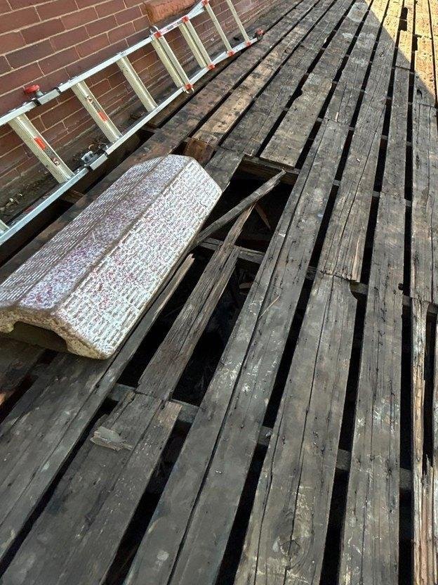 Roof plane exposed during tear-off showing open spaced board sheathing with gaps across entire roof slope on an Ogden, Utah home