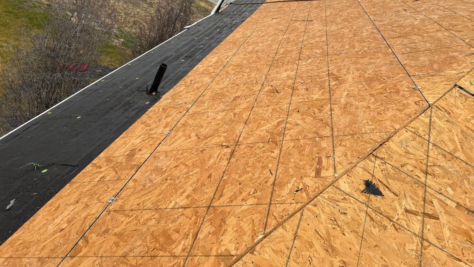 New 7/16-inch OSB roof decking panels and black self-adhering ice barrier membrane installed along eaves on a Highland, Utah home